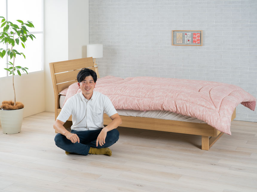 布団の前で微笑む江口