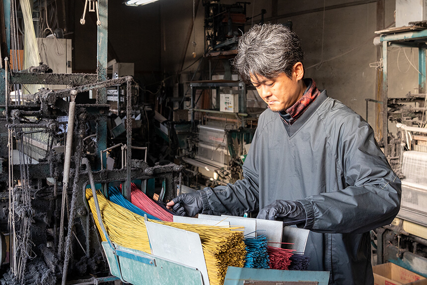 織機に入るい草をまっすぐに整えている様子。